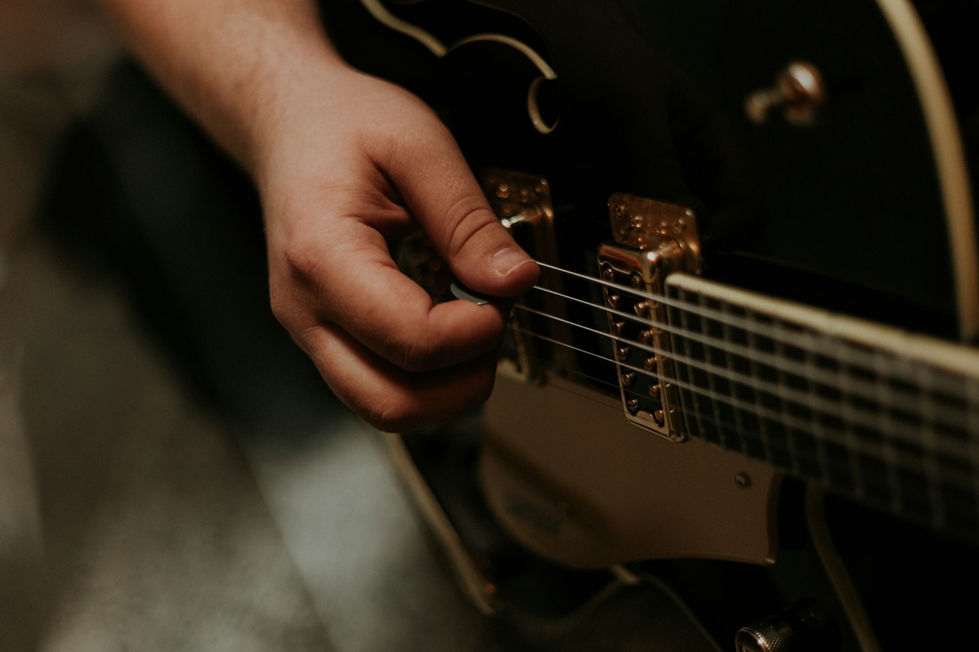 Close-up of a hand picking the strings of a hollow-body guitar